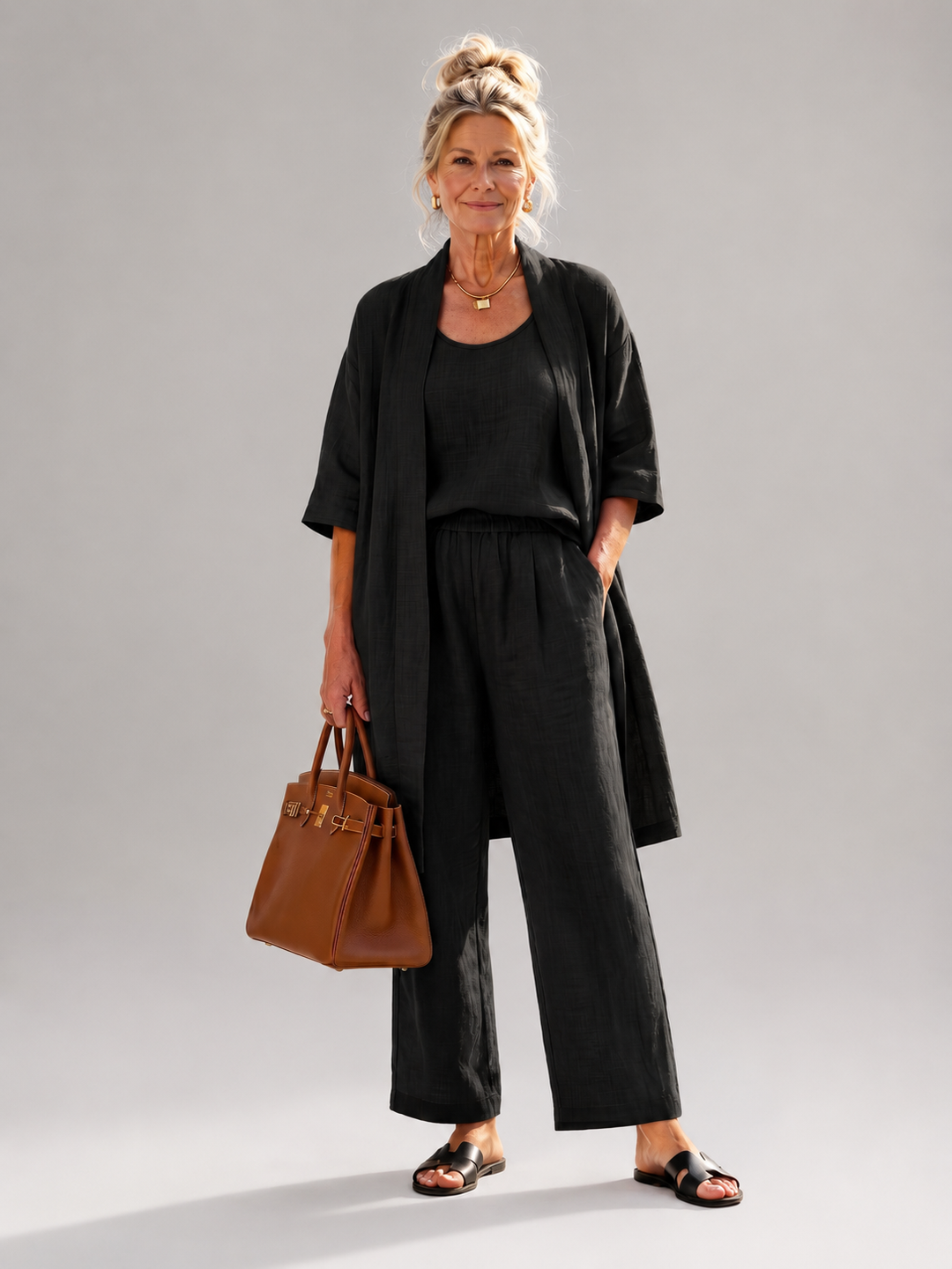 Femme portant un ensemble trois pièces avec haut, pantalon large et pièce ouverte assortie, coloris noir