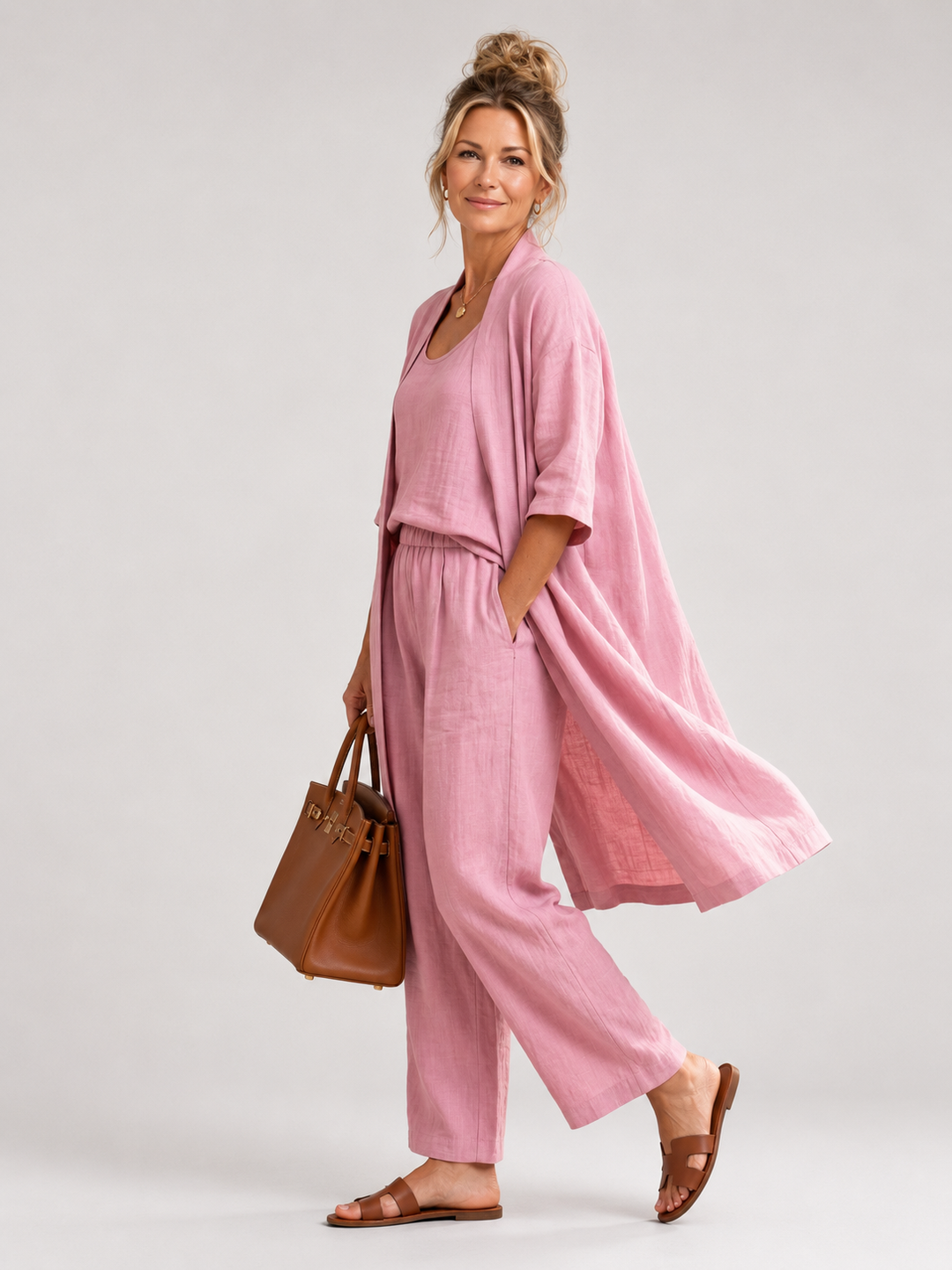 Femme portant un ensemble trois pièces avec haut, pantalon large et pièce ouverte assortie, coloris rose