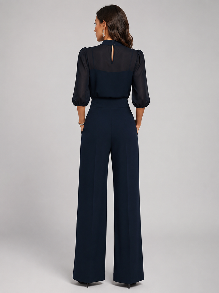 Femme portant un ensemble trois pièces avec blouse transparente et pantalon large, coloris bleu marine