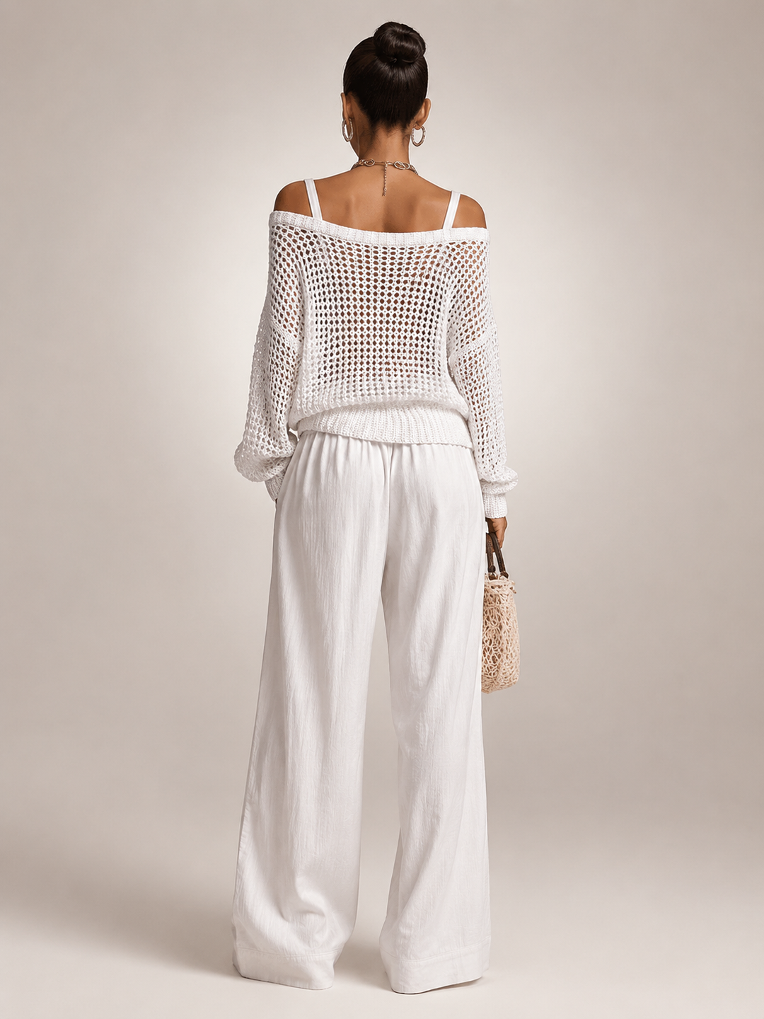 Femme portant un ensemble deux pièces avec haut en maille épaules dénudées et pantalon large, coloris blanc