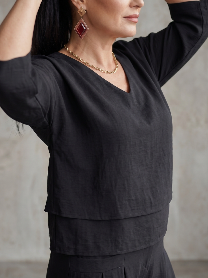 Femme portant un ensemble deux pièces avec haut superposé et pantalon à jambes larges, coloris noir