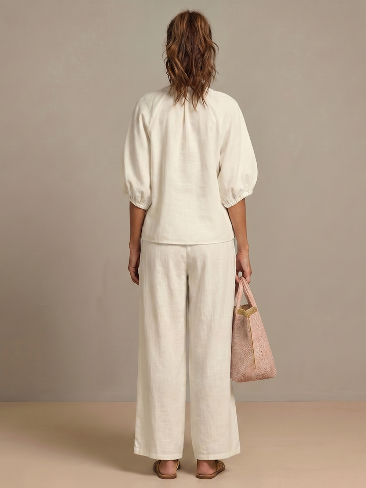 Femme portant un ensemble deux pièces avec blouse zippée et pantalon à jambes larges, coloris blanc