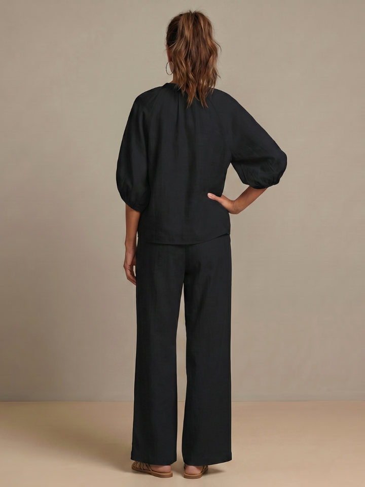 Femme portant un ensemble deux pièces avec blouse zippée et pantalon à jambes larges, coloris noir