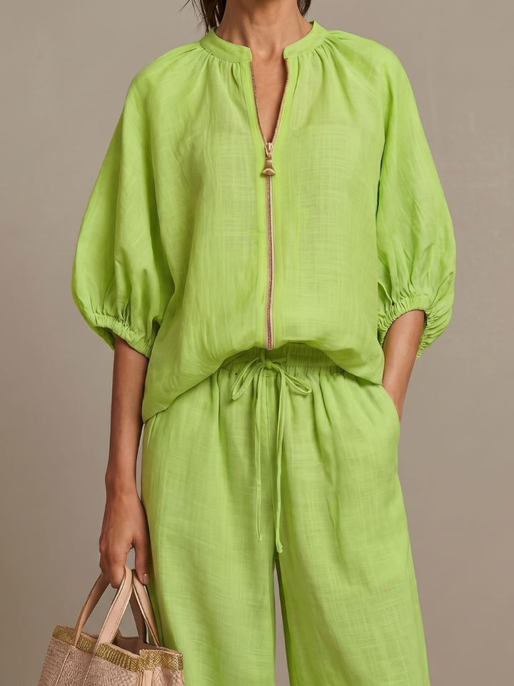 Femme portant un ensemble deux pièces avec blouse zippée et pantalon à jambes larges, coloris vert