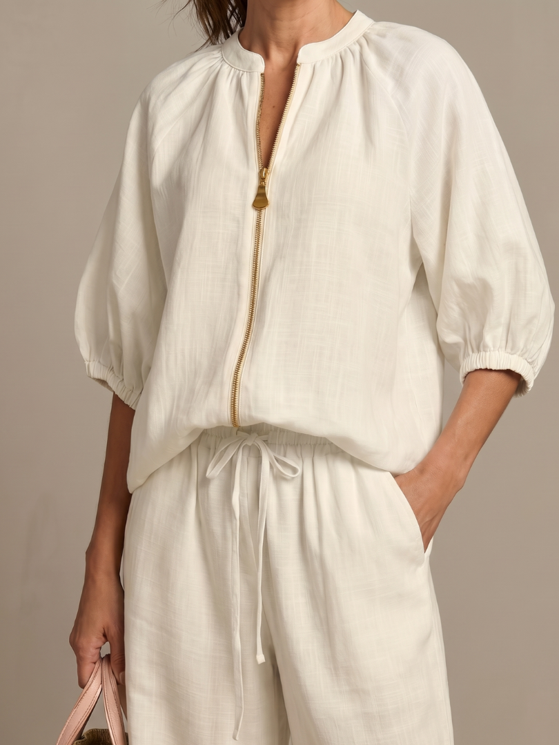 Femme portant un ensemble deux pièces avec blouse zippée et pantalon à jambes larges, coloris blanc