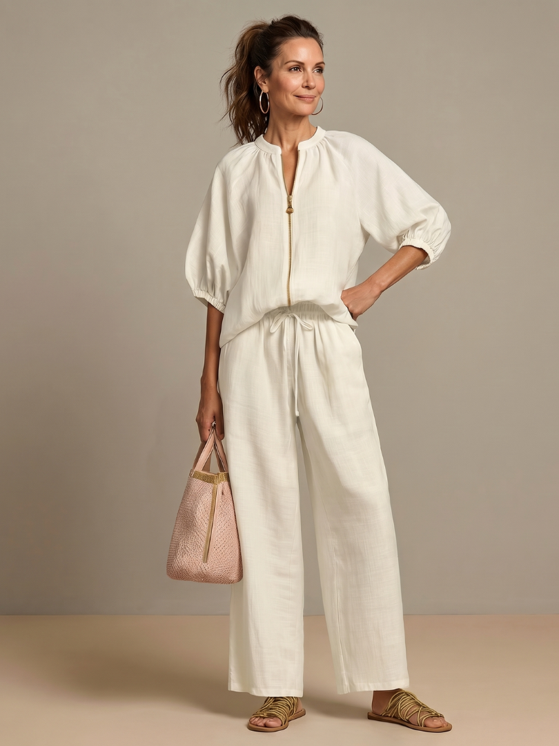 Femme portant un ensemble deux pièces avec blouse zippée et pantalon à jambes larges, coloris blanc