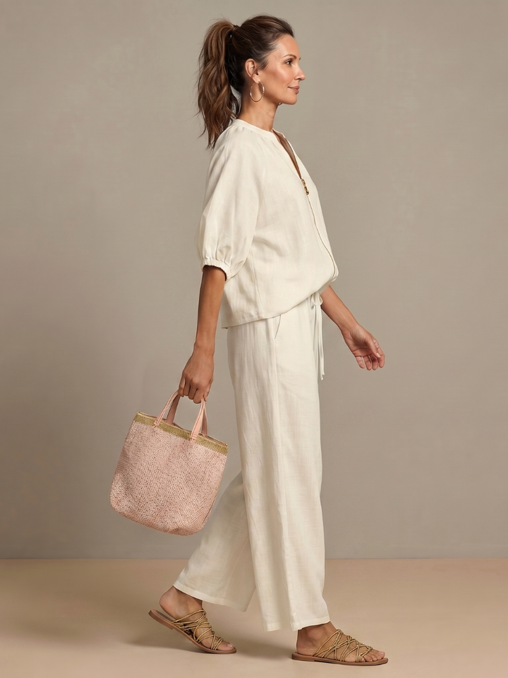 Femme portant un ensemble deux pièces avec blouse zippée et pantalon à jambes larges, coloris blanc