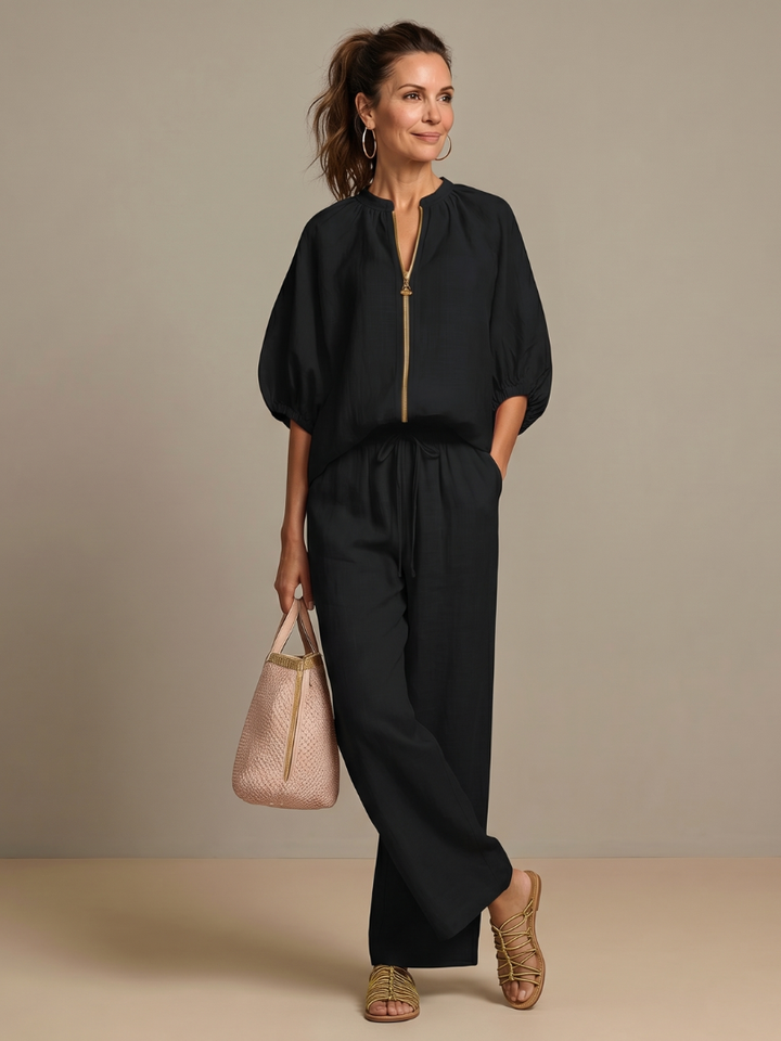 Femme portant un ensemble deux pièces avec blouse zippée et pantalon à jambes larges, coloris noir
